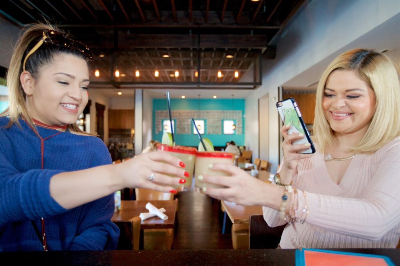 Stephanie Campos (right) uses her phone to photograph a toast with  friend, Aly Quayle,...