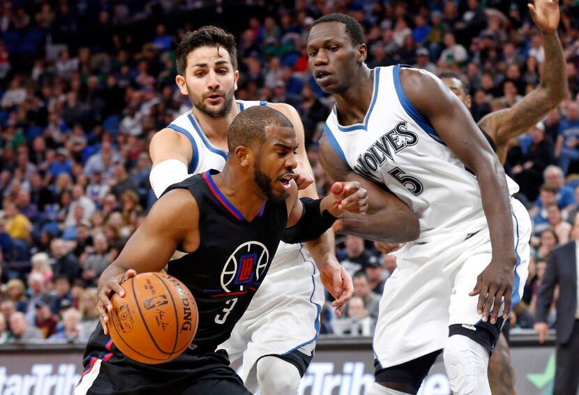 Los Angeles Clippers' Chris Paul drives around Minnesota Timberwolves' Ricky Rubio and...