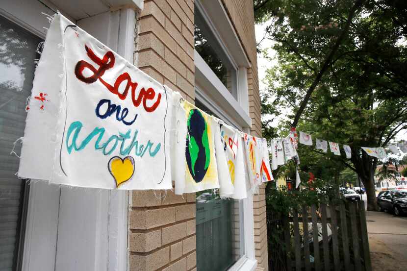 Painted cloth flags including one saying "Love One Another" are strung across a store along...