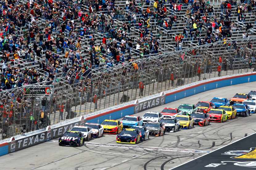 NASCAR driver and pole sitter Jimmy Johnson (left) leads the field of cars past the green...