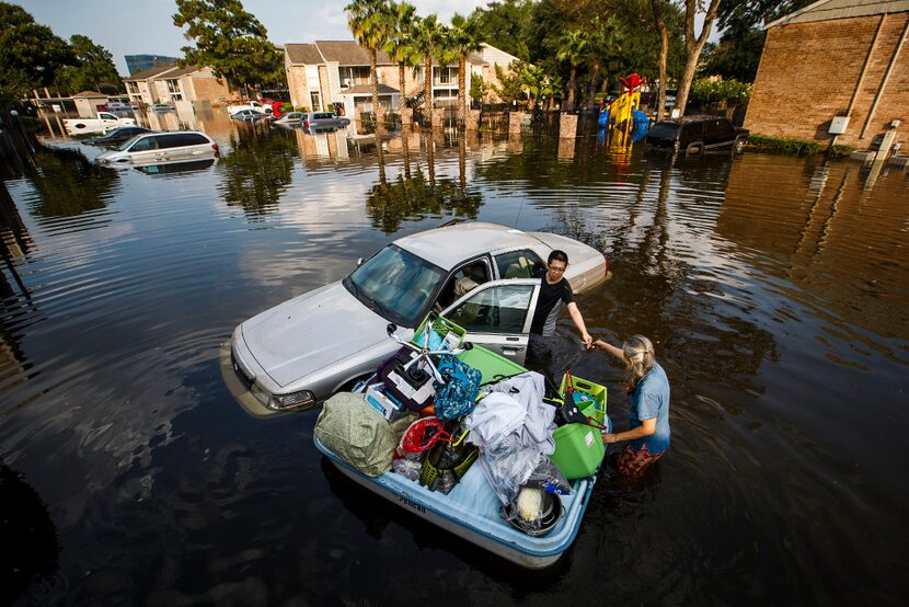 After loading a paddle boat with belongings from his apartment, Jeff Liu is helped by his...