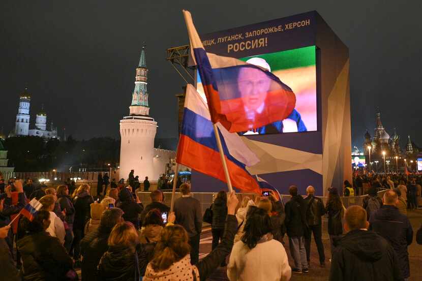 People watch on a large screen, as Russian President Vladimir Putin speaks during...