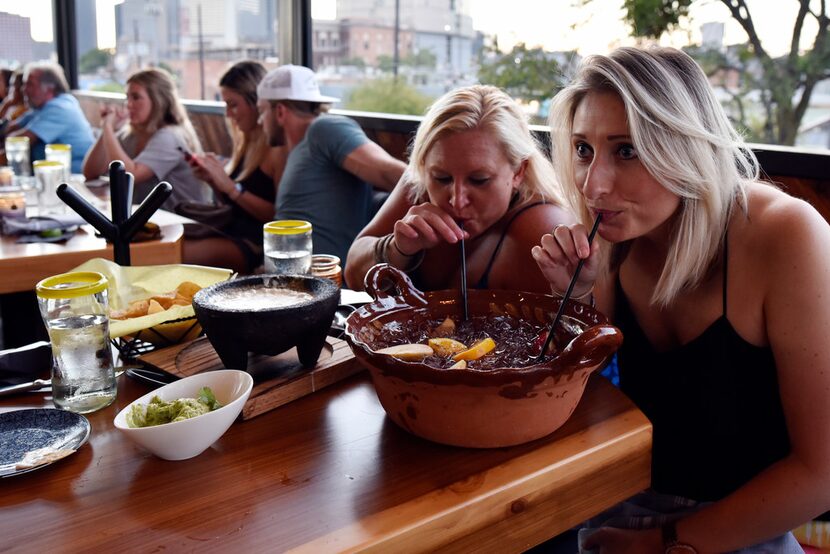 Prianne Sardoni, left, and Harriet Booth share a large margarita on the rooftop of Vidorra,...