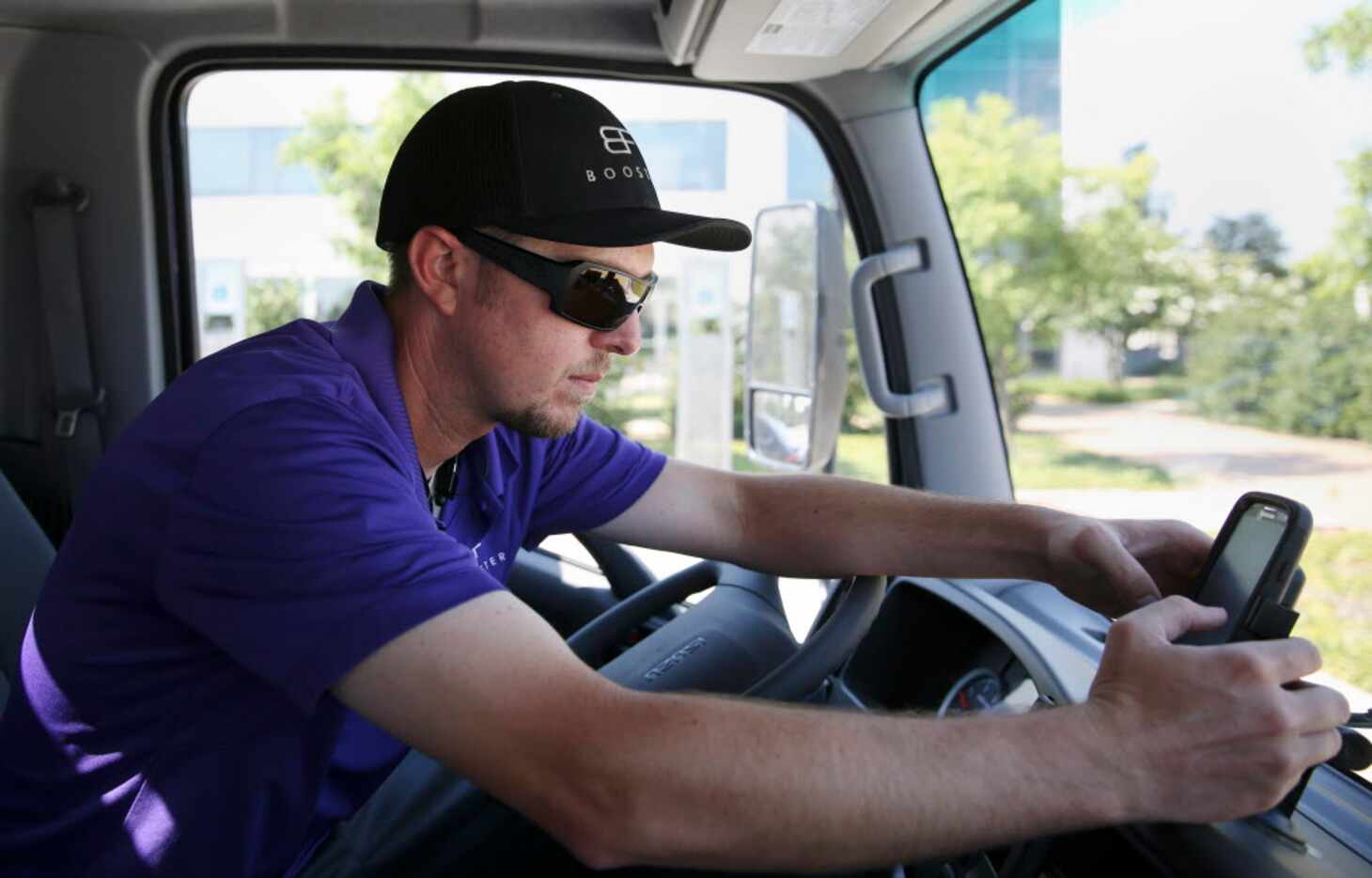 Booster driver Stephen Mainka checks the company app while navigating to customer cars at...