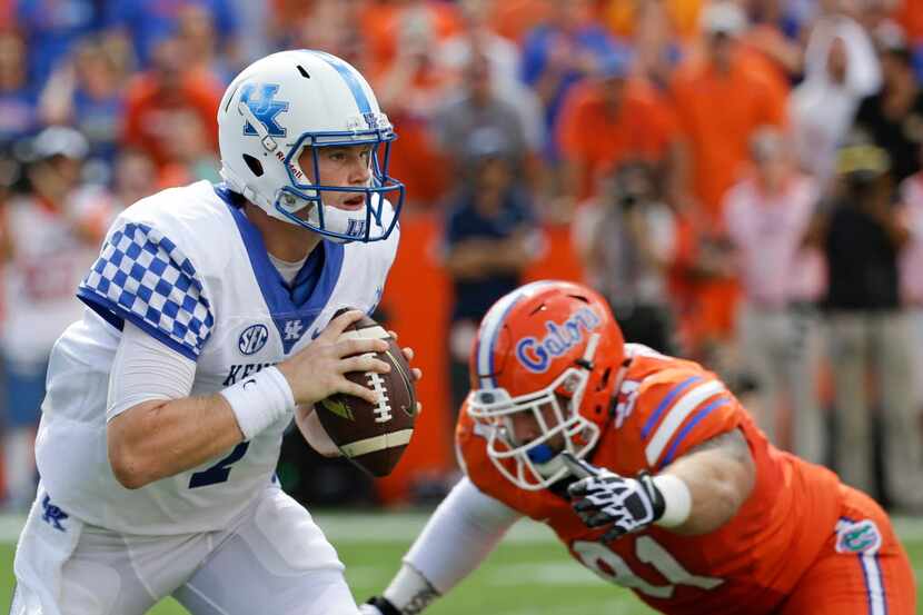 Kentucky quarterback Drew Barker, left, looks for a receiver as he is pressured by Florida...
