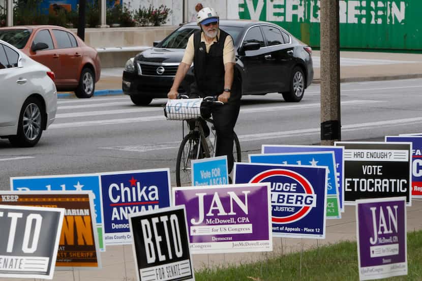 Gene Lantz rides past candidates' signs near the George L. Allen, Sr. Courts Building in...