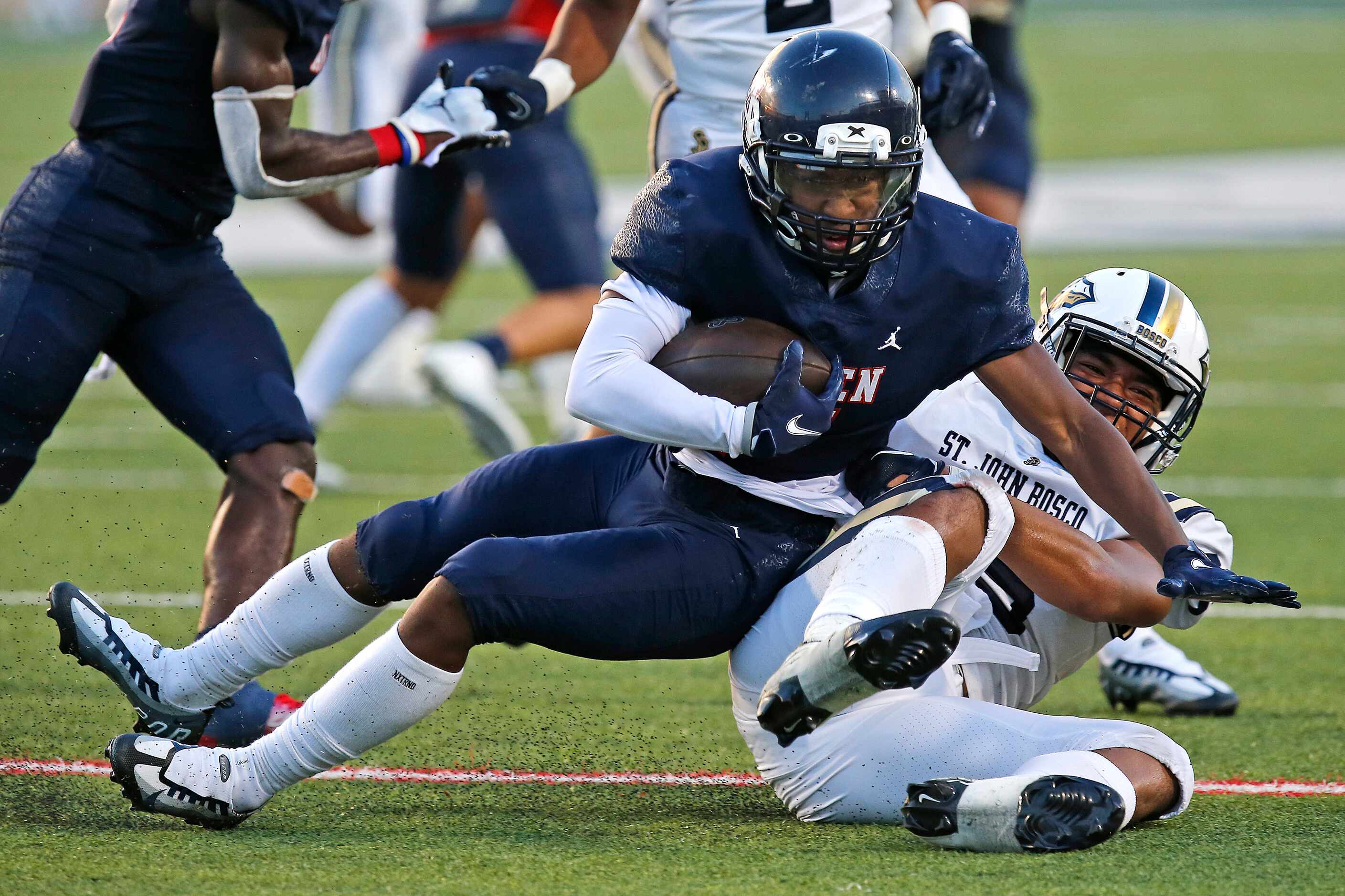 Allen High School running back Korey Mosley (7) falls onto St. John Bosco High School...