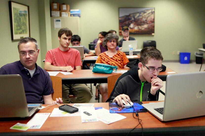 
Lewis Flanagin (left) and his son Brendan Flanagin, 13, use their laptops to work during...