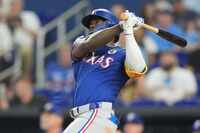 Texas Rangers' Adolis Garcia hits a solo home run during the sixth inning of a baseball game...