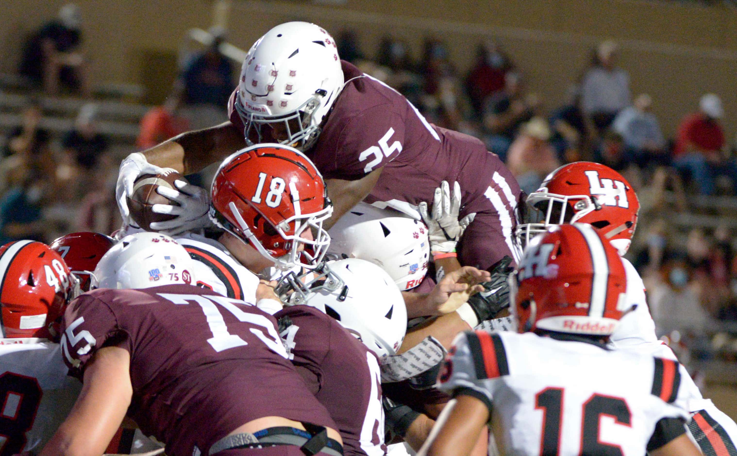 Plano’s Tylan Hines (25) leaps over the pile for a touchdown in the first quarter of a high...