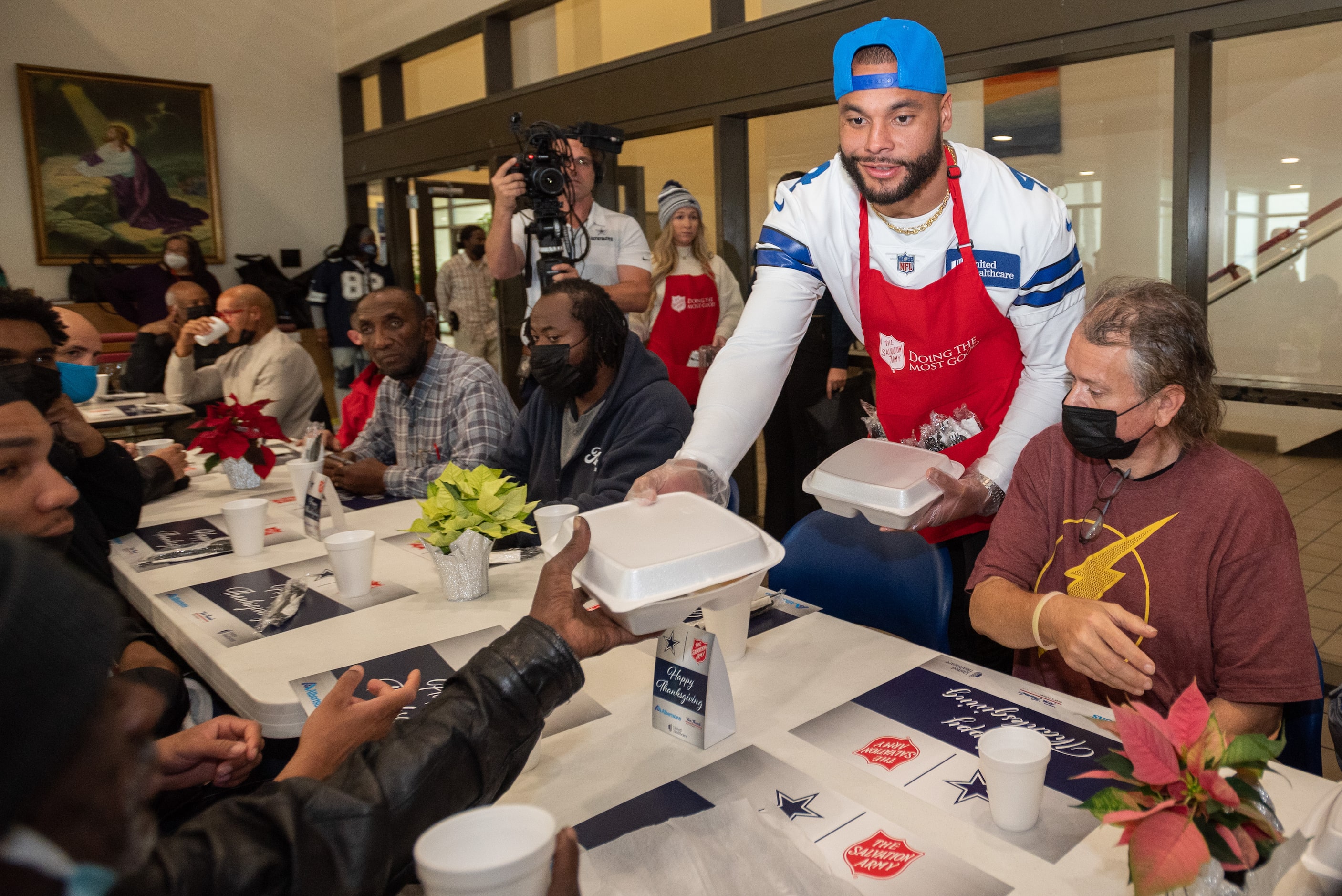 Dallas Cowboys starting quarterback Dak Prescott hands Thanksgiving meals to men and women...