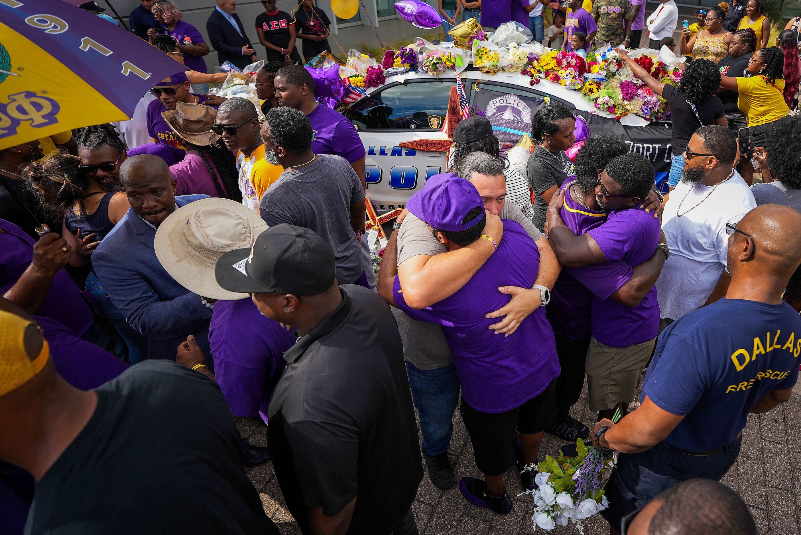 Dallas firefighter Kevin Wickware (facing at center) hugs fraternity brother Kenard Farr...