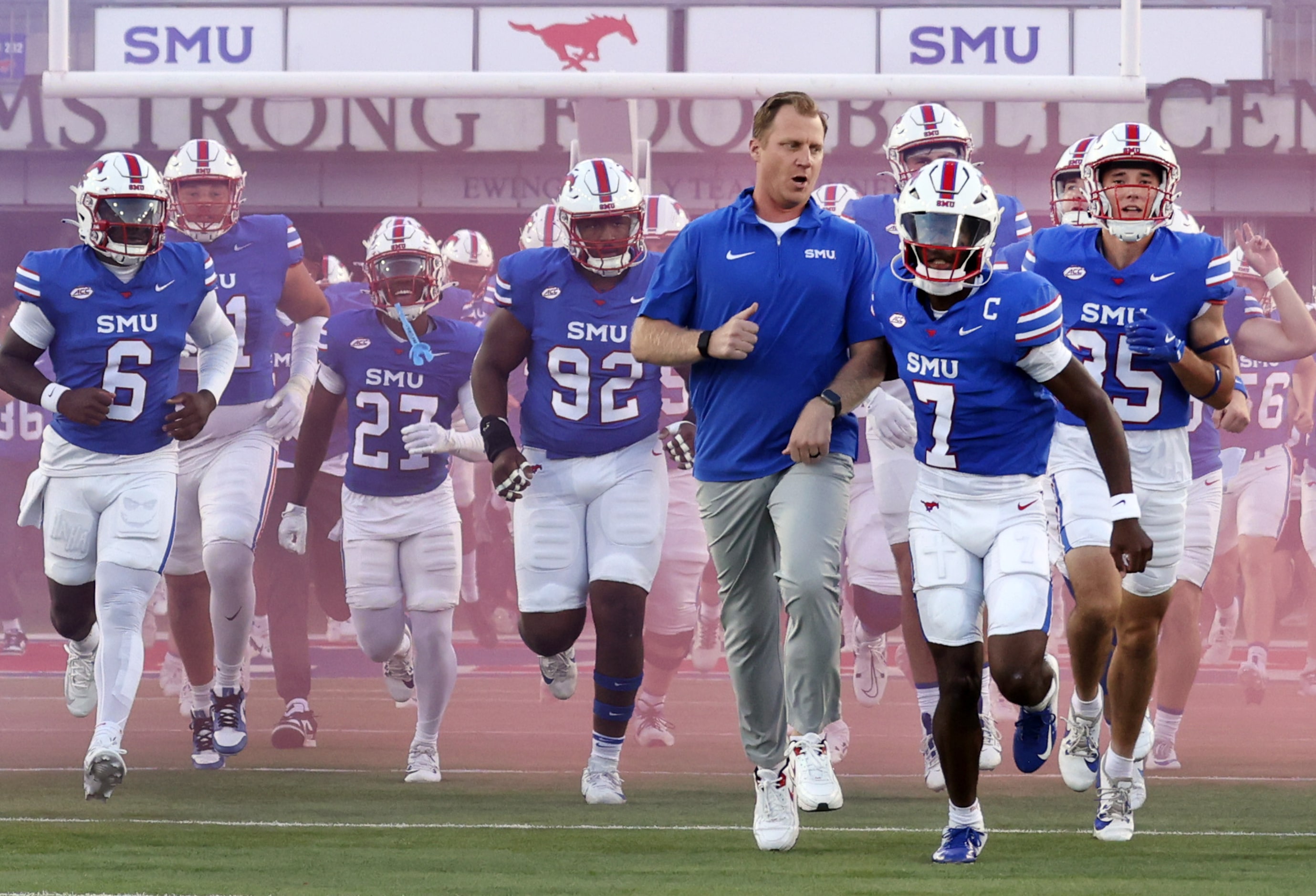 SMU Mustangs head coach Rhett Lashlee runs alongside quarterback Kevin Jennings (7) as the...