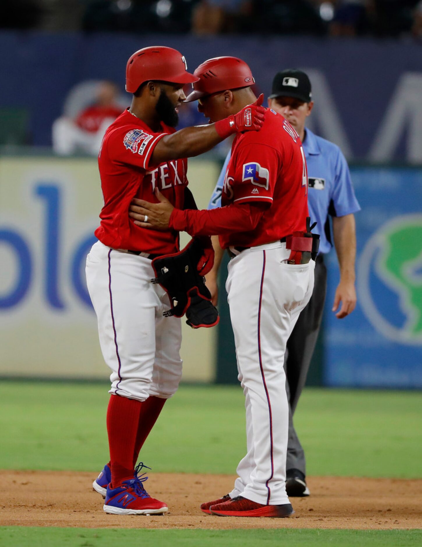 Texas Rangers' Danny Santana, left, gestures to the dugout as he talks with first base coach...