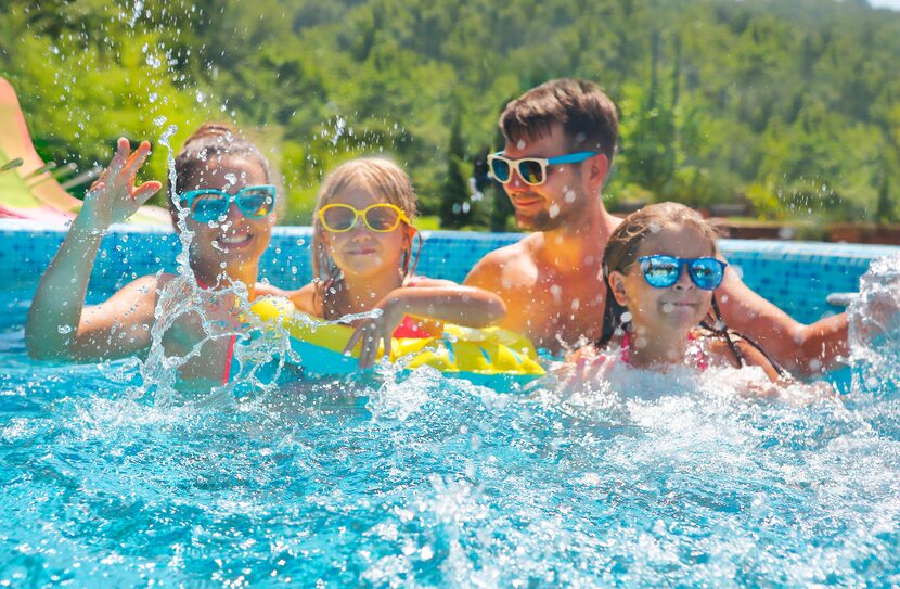 Happy family with two kids having fun in the swimming pool.