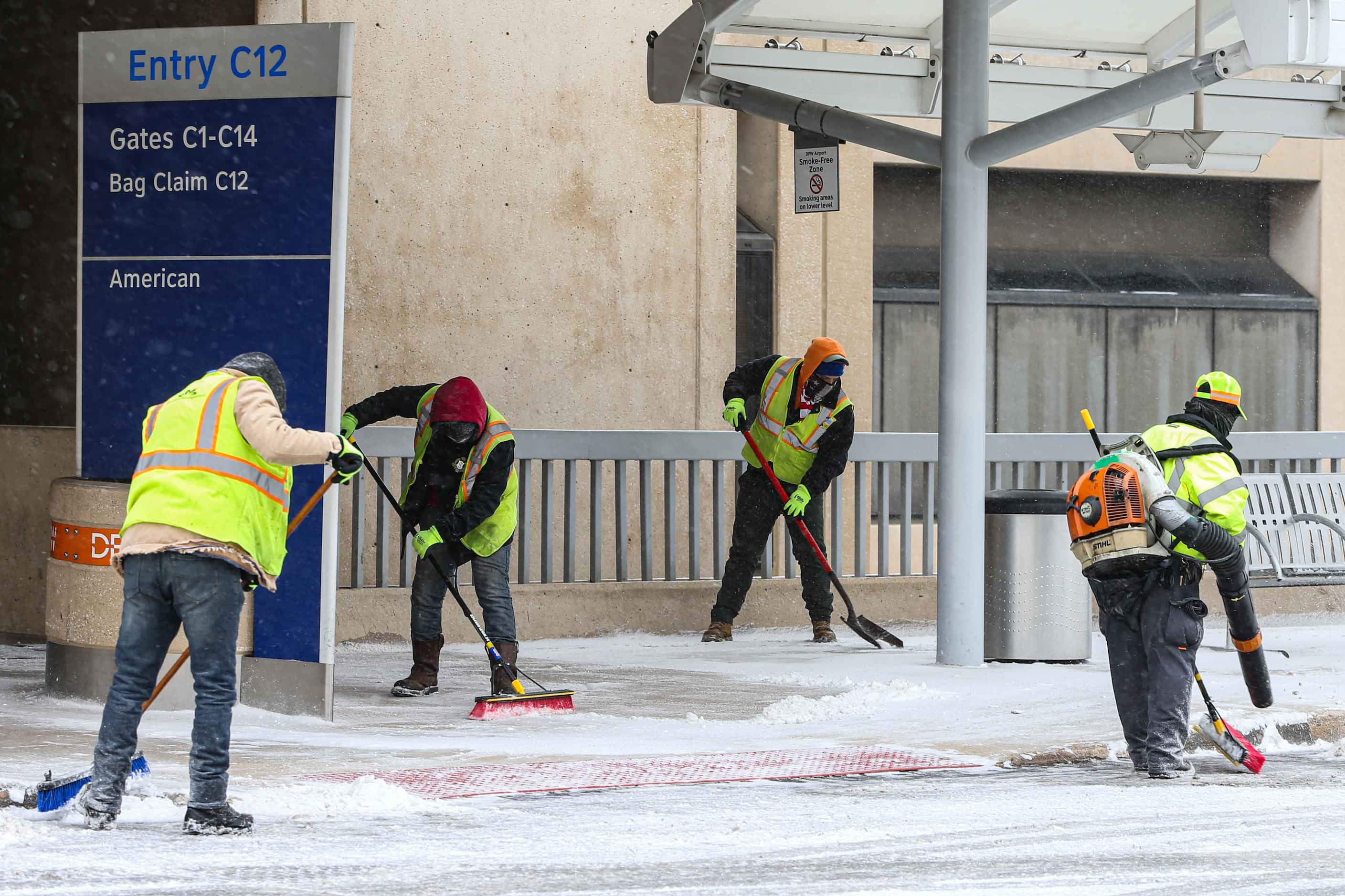 Workers keep the sidewalks clear as snow, ice decend over DFW International Airport....