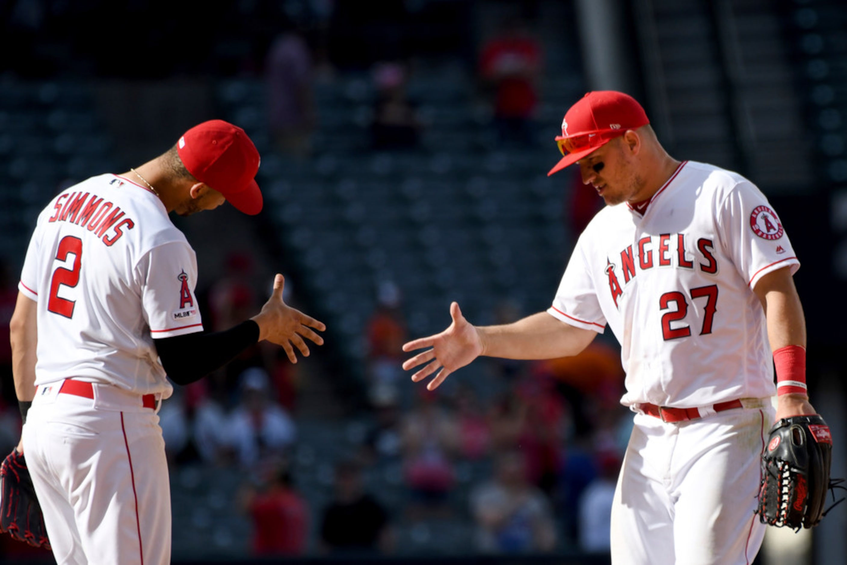 Los Angeles Angels' Andrelton Simmons (2) and Mike Trout (27) line up a handshake after the...