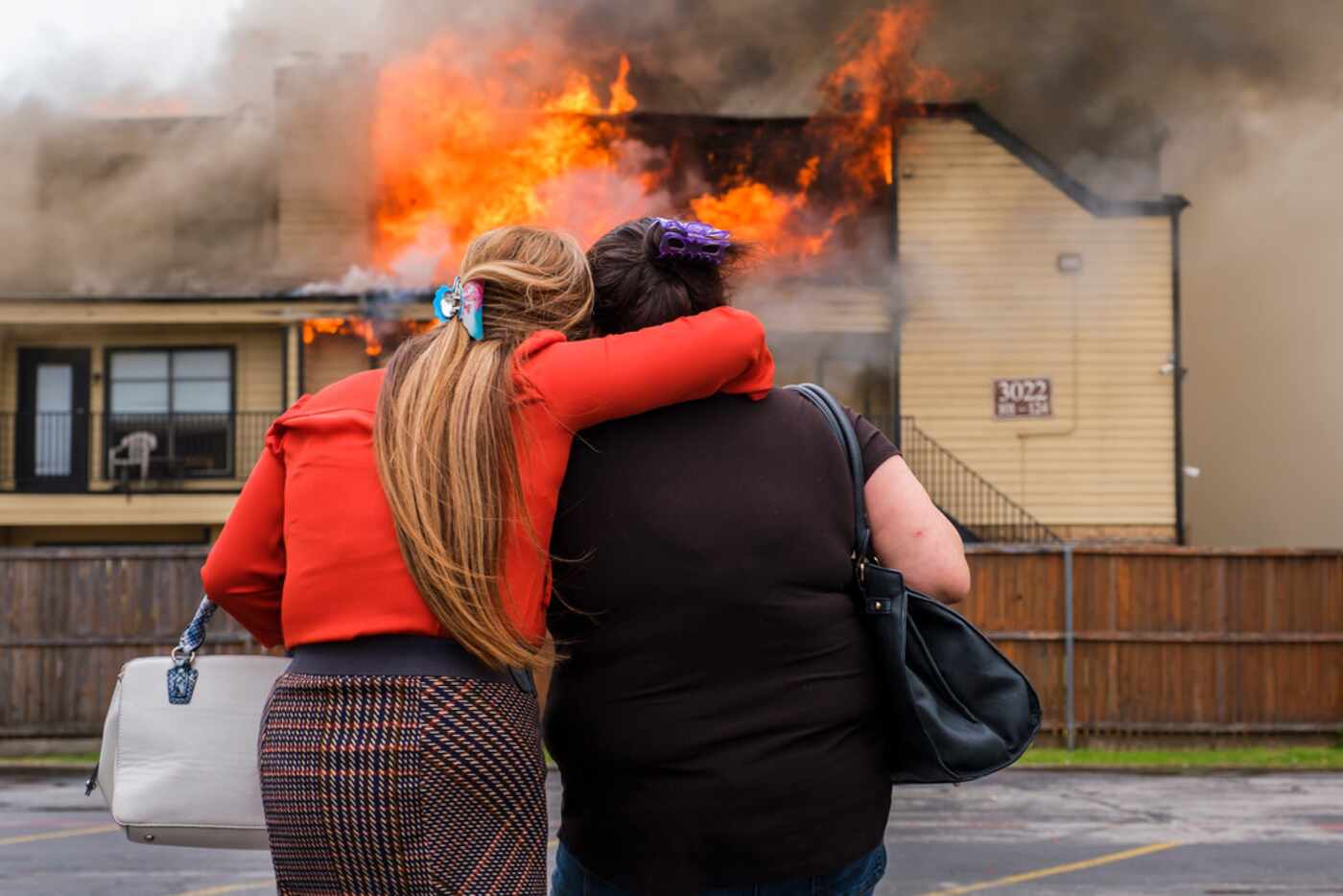 Jeannie Perez Stine (right) is consoled by a neighbor as she watches as Dallas Fire-Rescue...