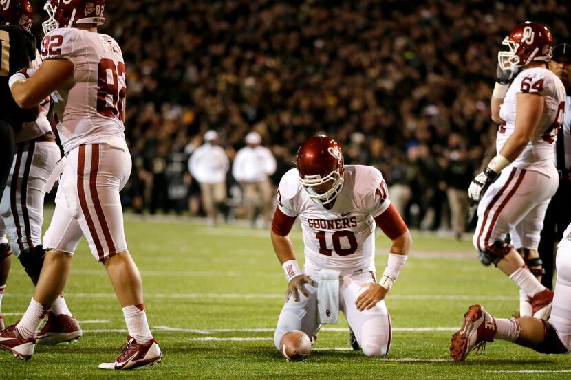 Oklahoma quarterback Blake Bell (10) kneels over the ball after being stopped short of the...