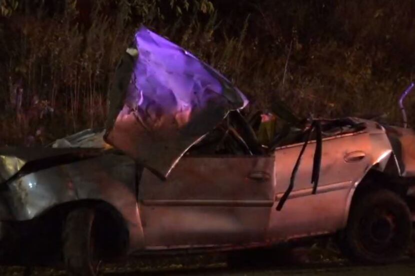 A car lies crumpled on the side of the road after it hit a telephone pole on West Davis...