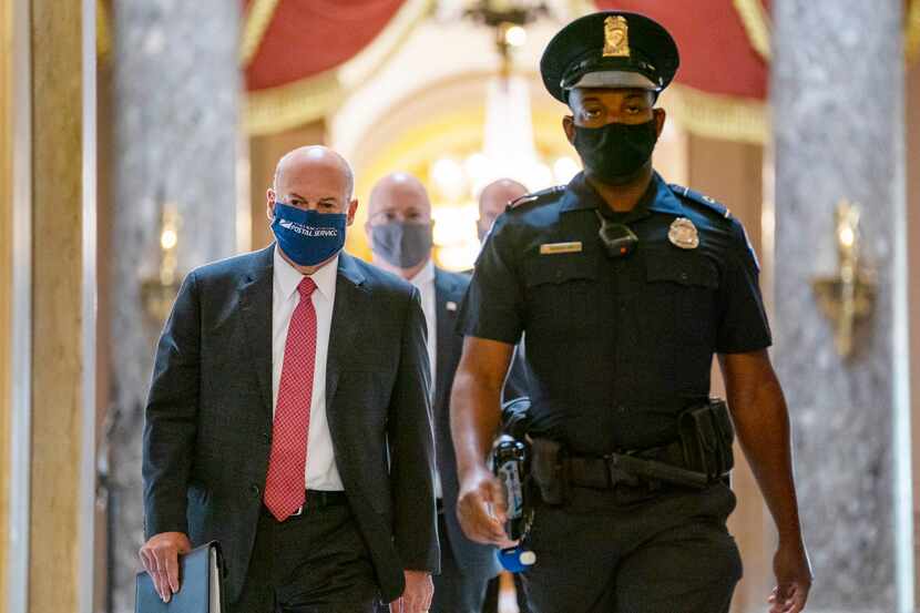 FILE - In this Aug. 5, 2020, file photo, Postmaster General Louis DeJoy (left) is escorted...