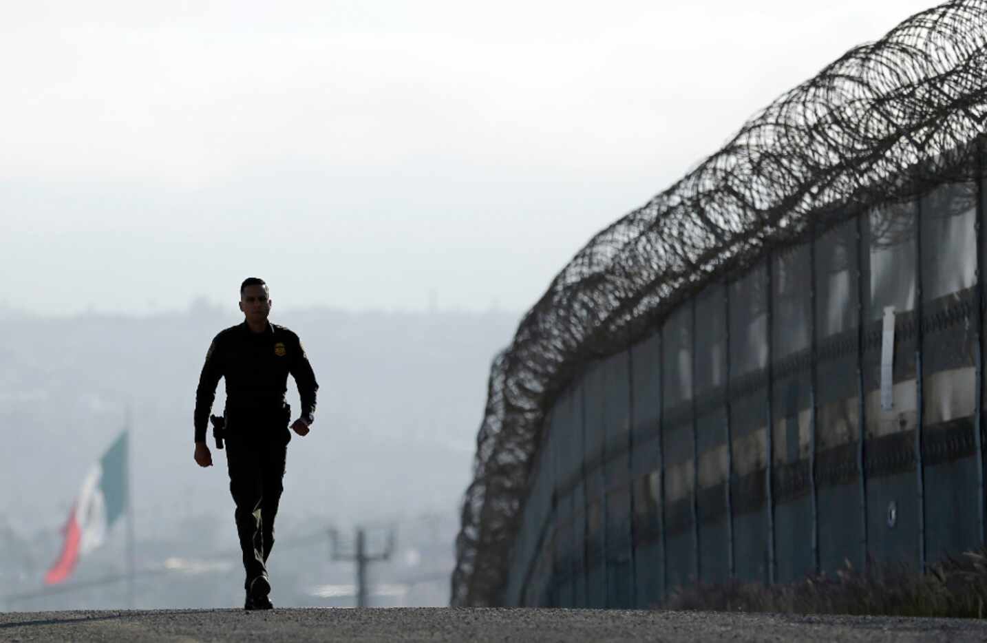 Border Patrol agent Eduardo Olmos walks near the secondary fence separating Tijuana, Mexico,...