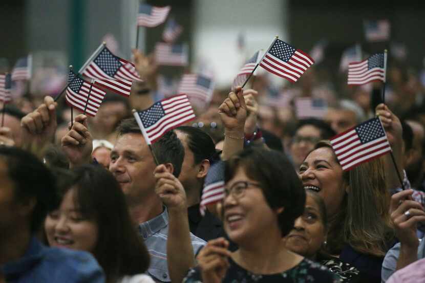 People wave American flags at a naturalization ceremony on July 25, 2018 in Los Angeles,...