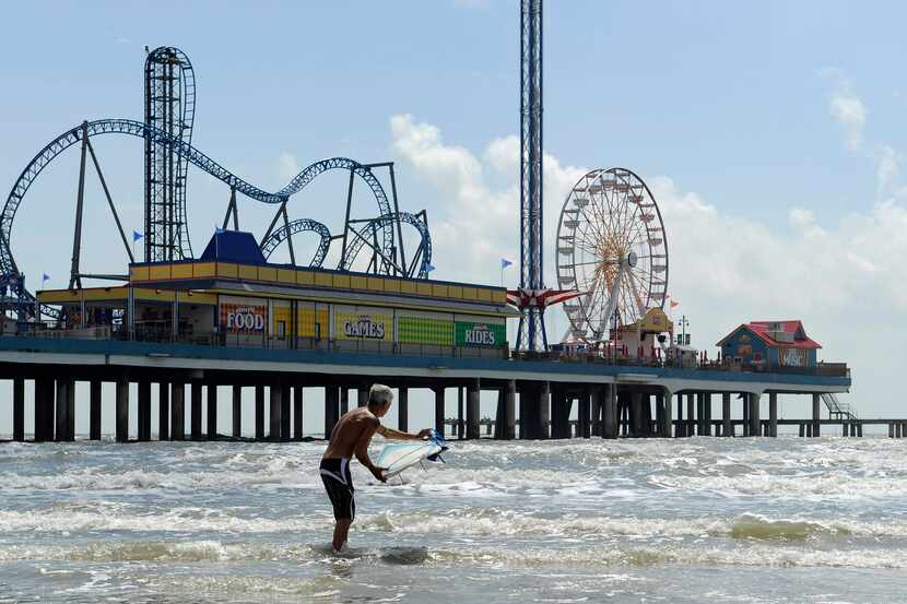 In this Sept. 11, 2013 photo, a surfer heads into the water near the Galveston Island...