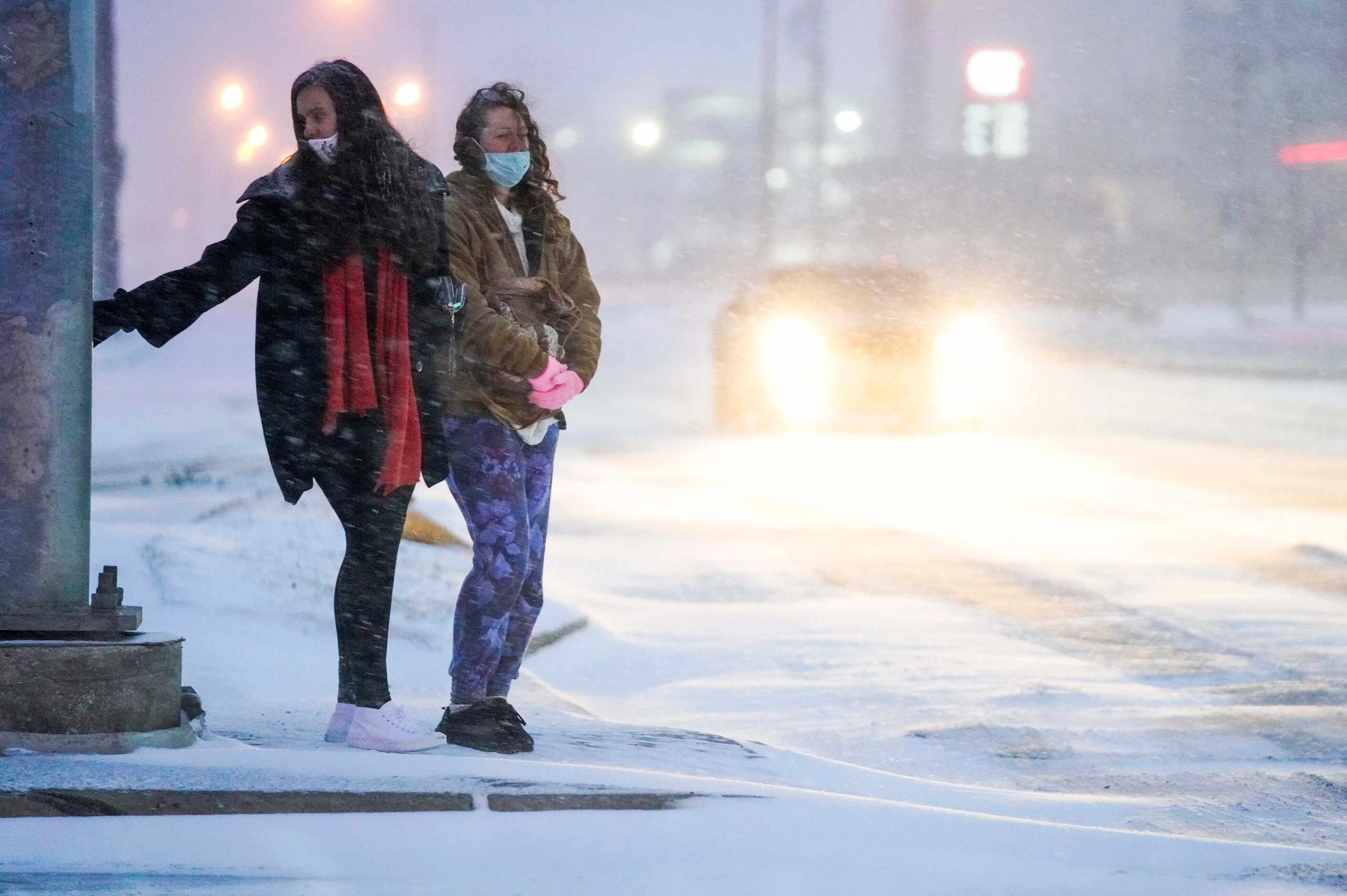 Miryea Gist (left) and Mikaela Dudley wait in heavy snow to cross Mockingbird Lane near...