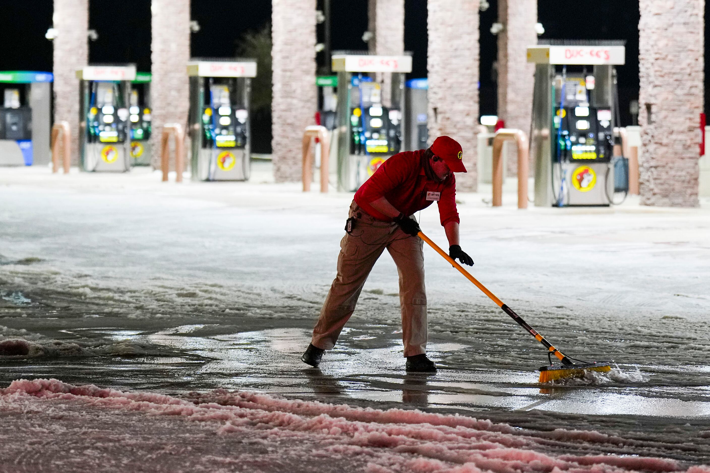 Employee Christopher Scroggins clears snow and ice from walkways in the parking lot at...