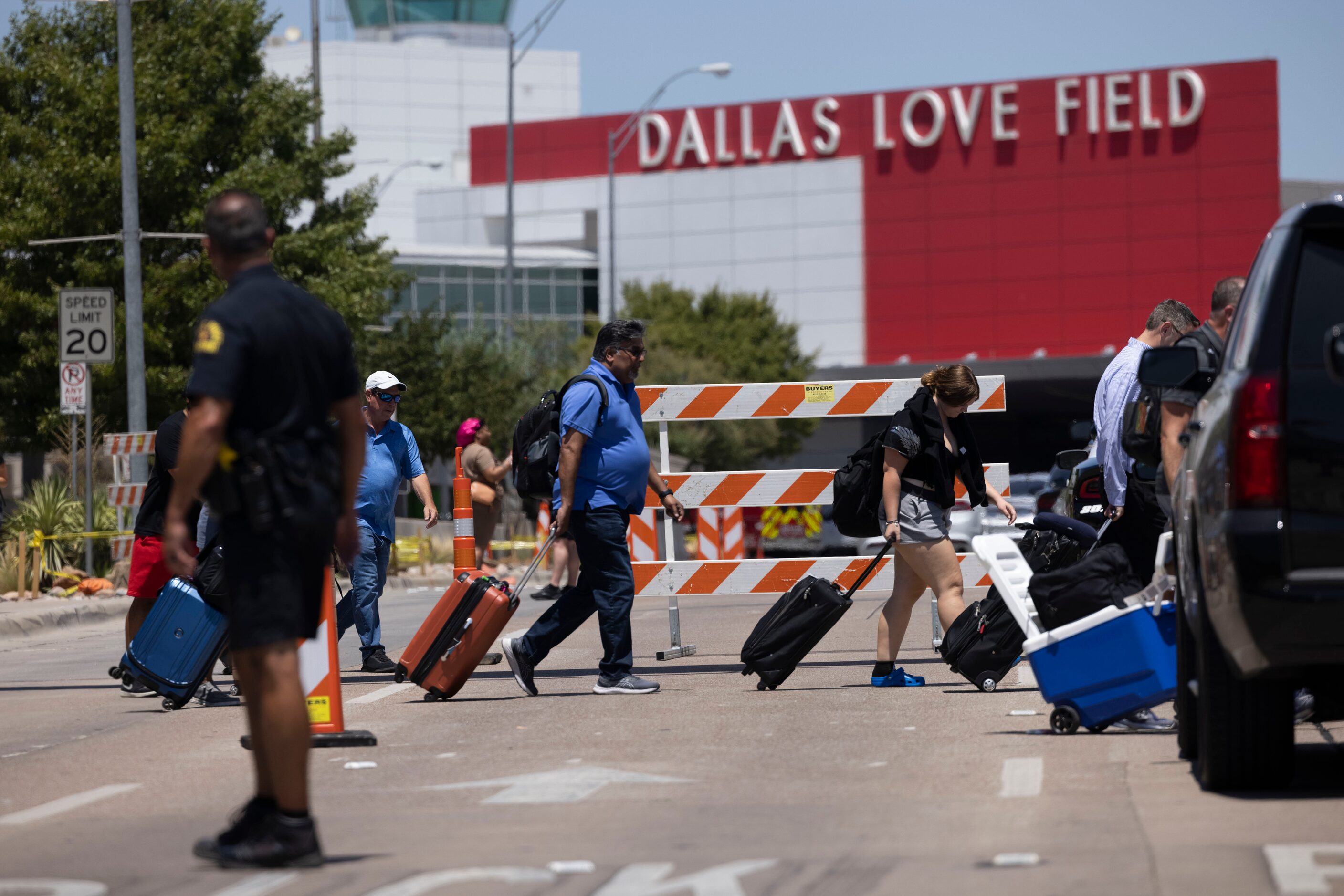 Travelers leave as Dallas police investigate reports of a shooting at Dallas Love Field...