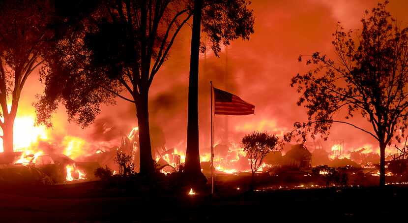 An American flag still fly's as as structures burn in Coffey Park, Monday Oct. 9, 2017. More...