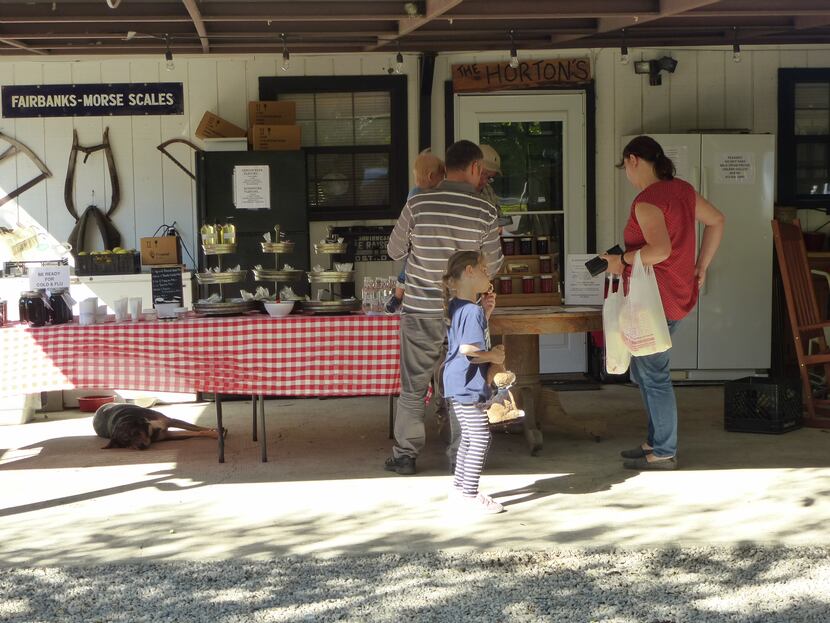 Steven Horton helps some Saturday shoppers with cow's and goat's milk, pastured meats,...
