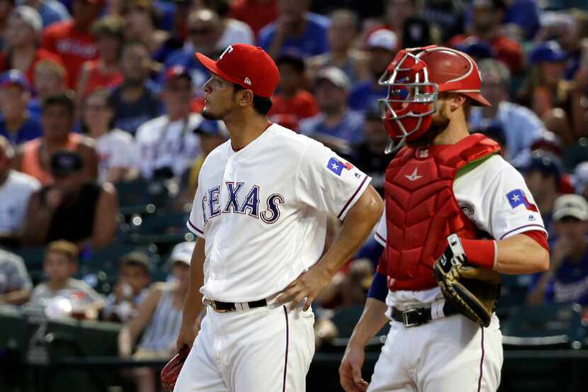 Texas Rangers starting pitcher Yu Darvish of Japan walks by catcher Jonathan Lucroy, right,...