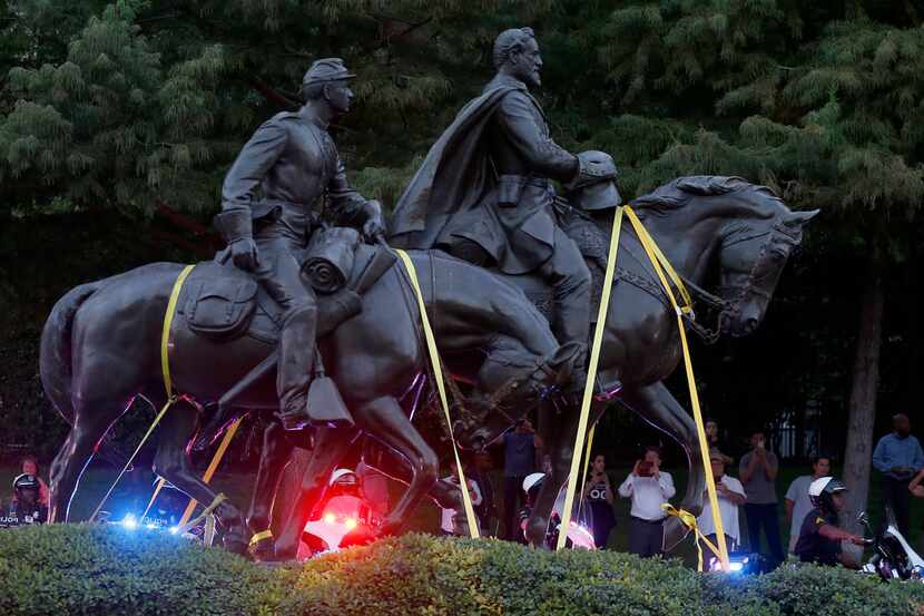 Motorcycle officers start to escort a truck carrying the Robert E. Lee statue at Robert E....