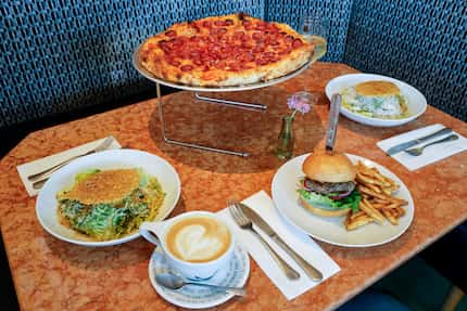 A pepperoni pizza, Caesar salads, a burger and a latte fill a table at The Meteor in Dallas.