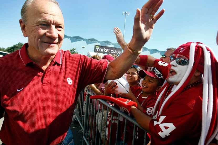 Former Oklahoma and Dallas Cowboys coach Barry Switzer slaps hands with Oklahoma fans as he...