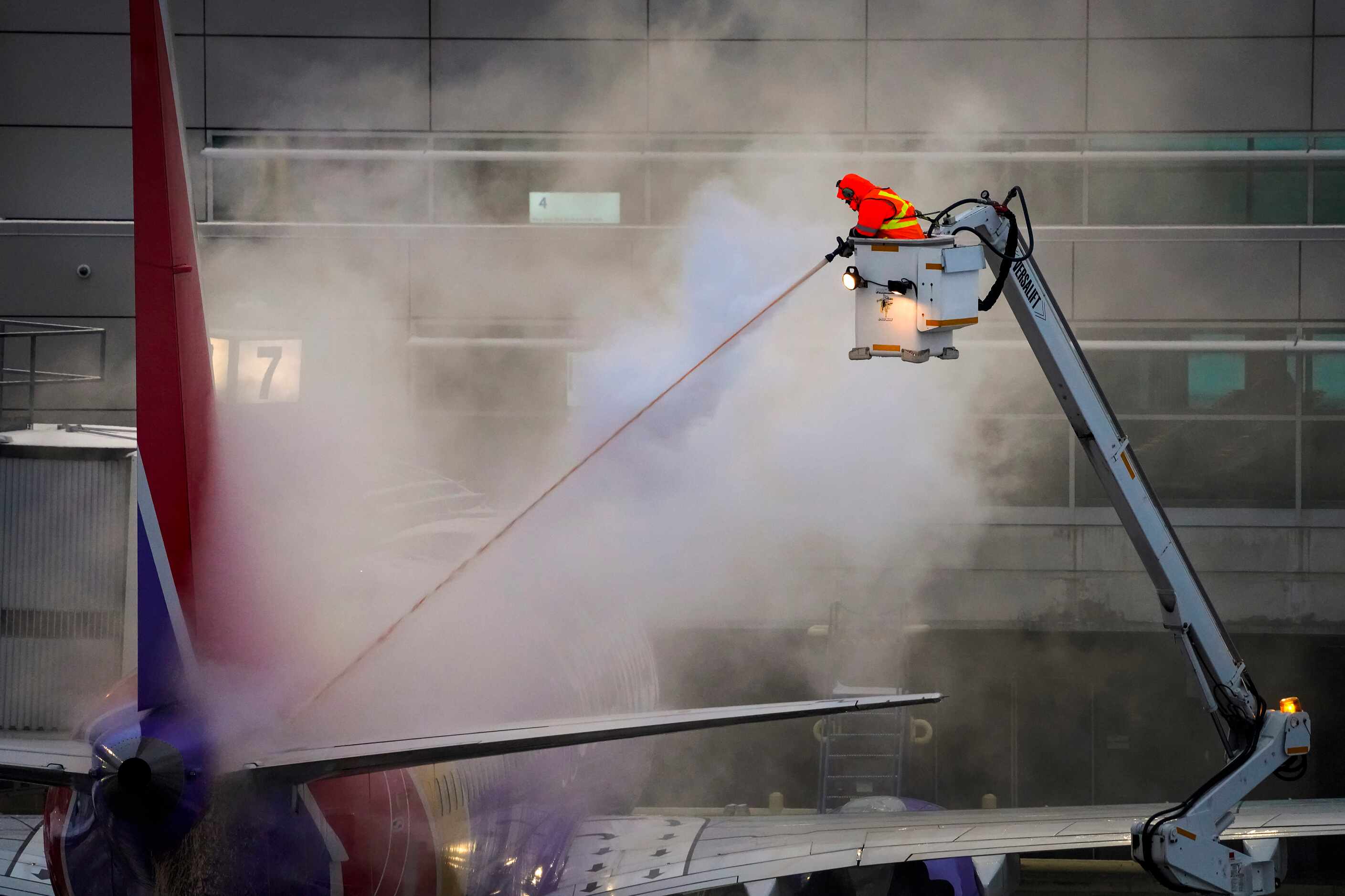 A worker sprays deicing fluid on a Southwest Airlines plane at the gates of Dallas Love...