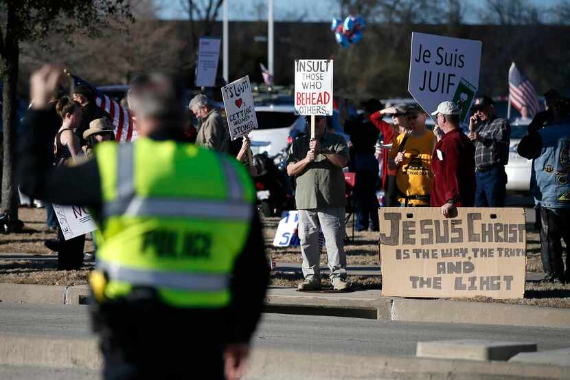 
A Garland police officer directs vehicle traffic as anti-Muslim protesters gather outside...