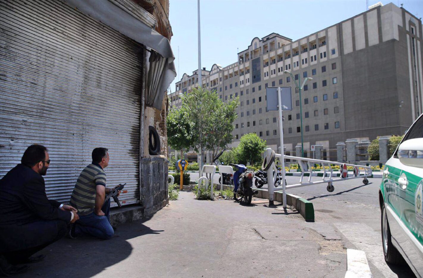 Security personnel crouch down outside Iran's parliament building after a suicide attack...