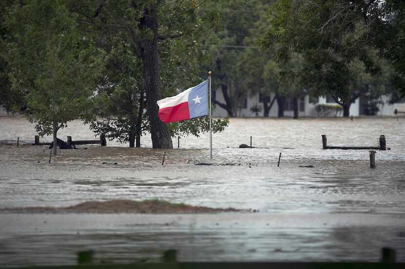 A Texas flag flies over floodwaters caused by Tropical Storm Harvey in La Grange, Texas,...