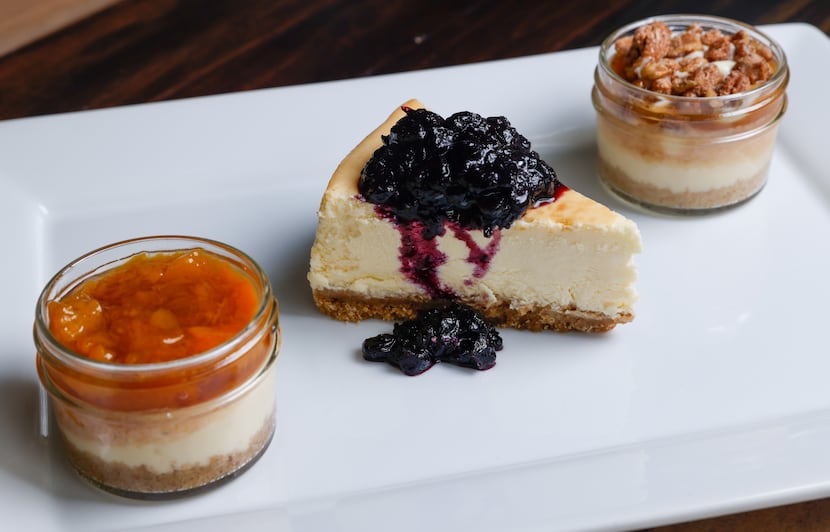 A slice of classic cheesecake with blueberry preserves sits between a jar of It’s Britney,...