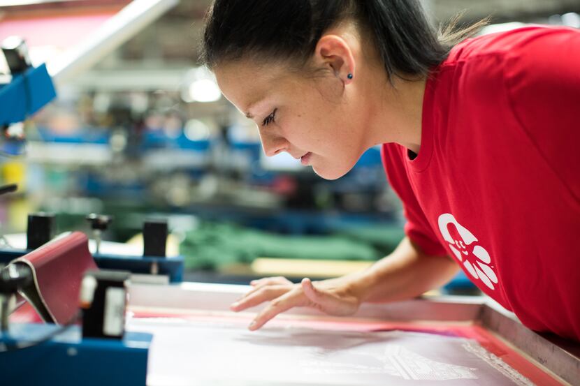 A Custom Ink worker checks on a design on the production floor. The company makes custom...