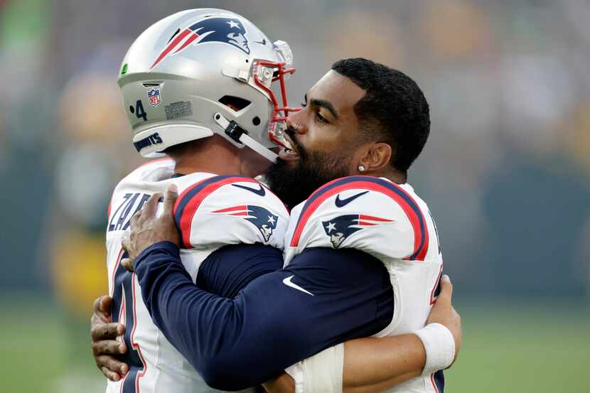 New England Patriots running back Ezekiel Elliott (15) hugs quarterback Bailey Zappe (4)...