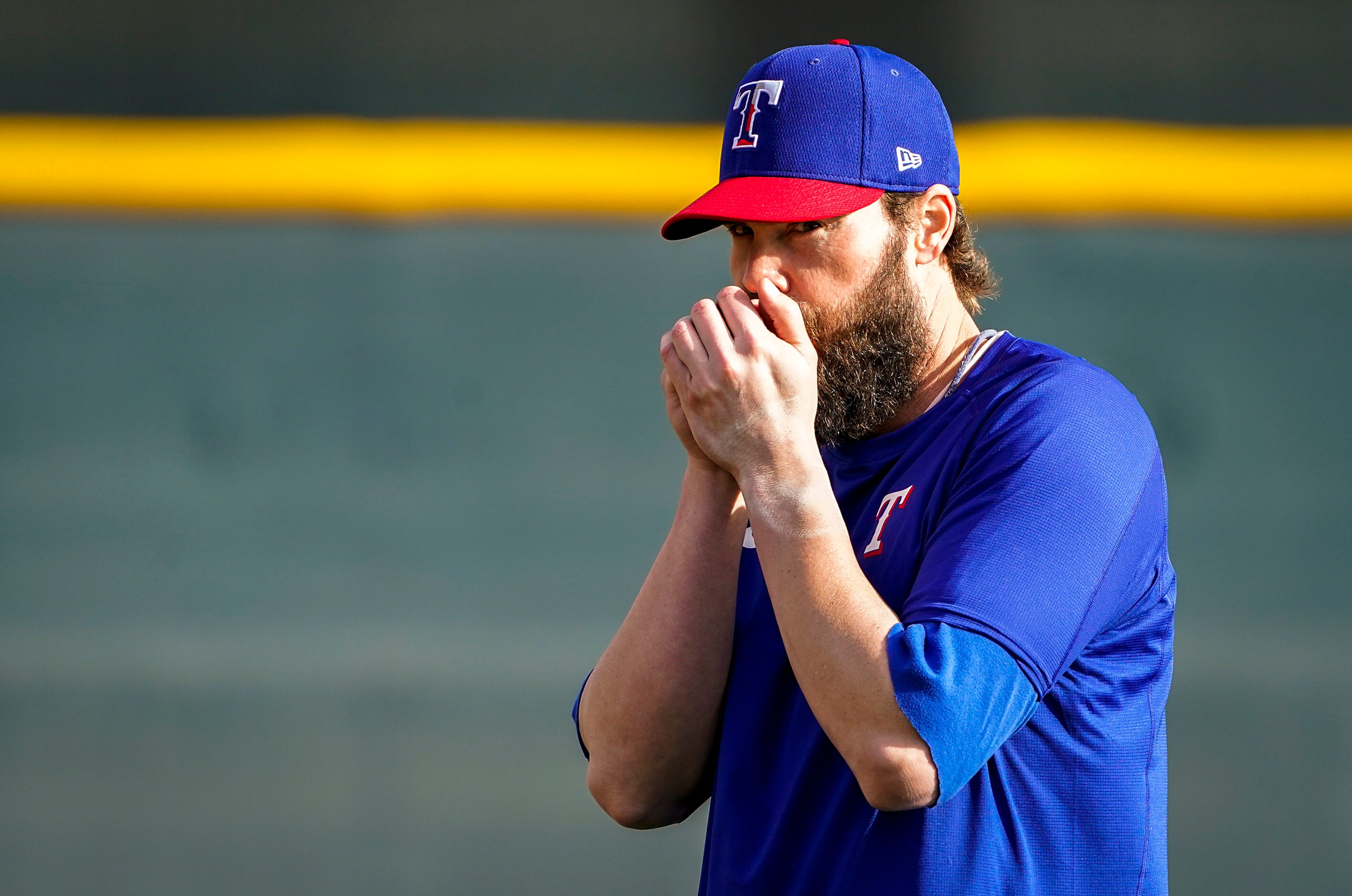 Texas Rangers pitcher Tim Dillard warms his hands on a chilly morning before playing catch...