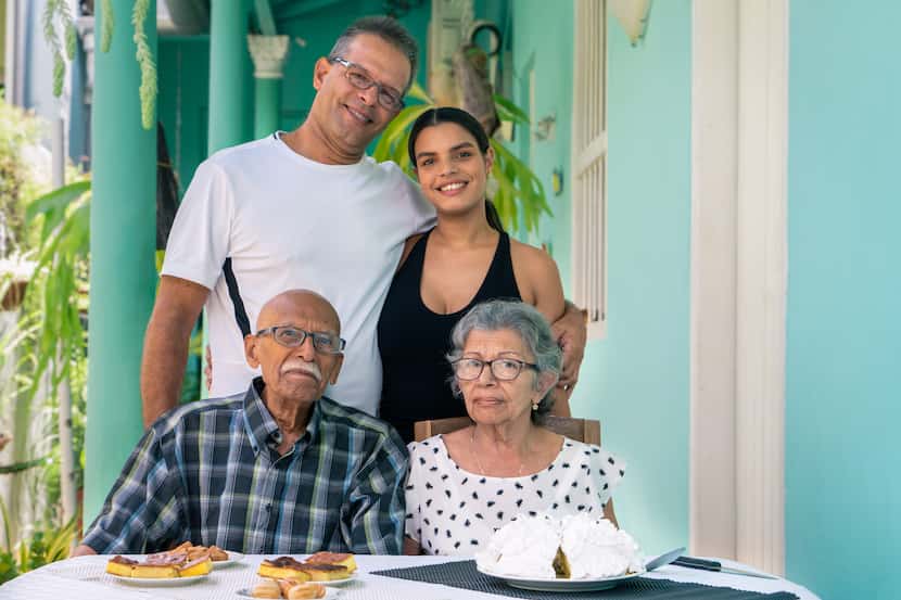 Elderly couple wearing eyeglasses sitting at a table and a man and a young woman standing...