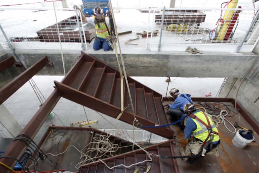 Construction workers install part of a stairwell on the 16th floor of the new Parkland...