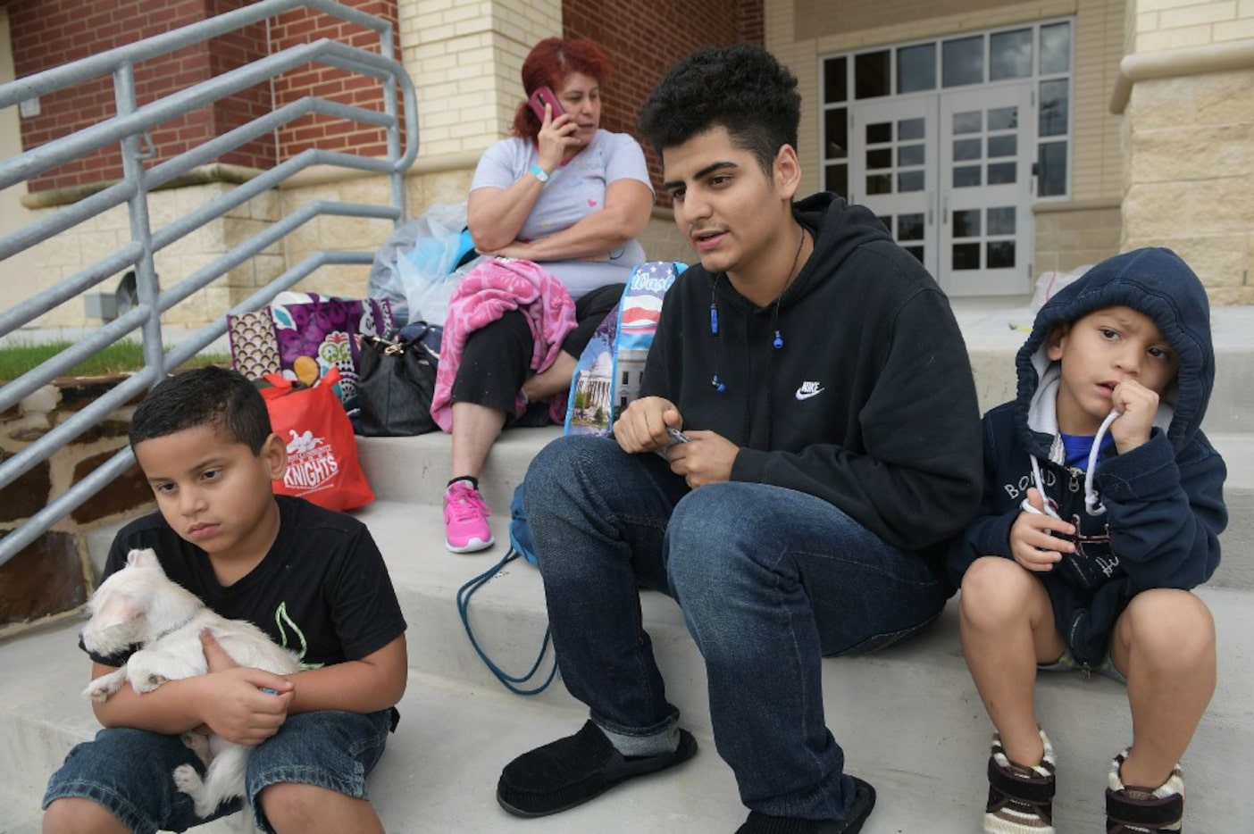 Susan Garcia talks on the phone while waiting for a ride with her sons Joshua Lopez (from...