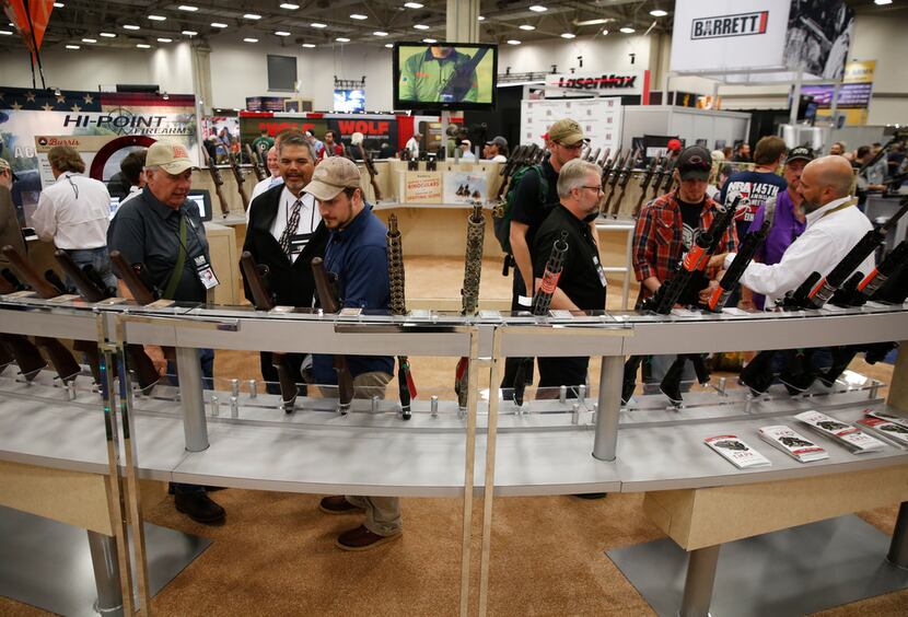 Men look at scopes at the NRA Annual Meeting & Exhibits at Kay Bailey Hutchison Convention...