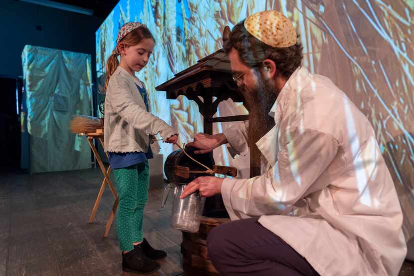 Wearing a kippah with a matzah design, Rabbi Levi Raskin, right, shows a first grade student...